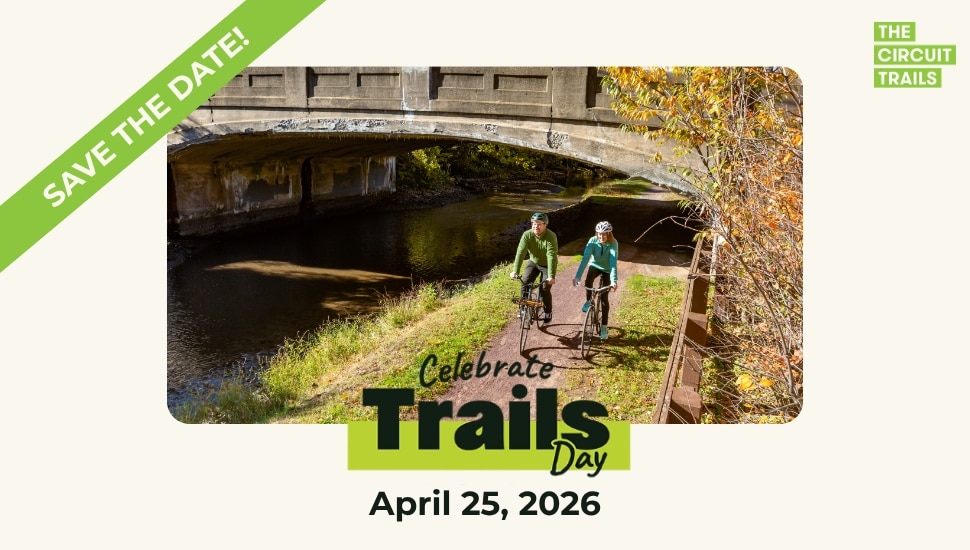 Couple rides bikes on a trail alongside a river.