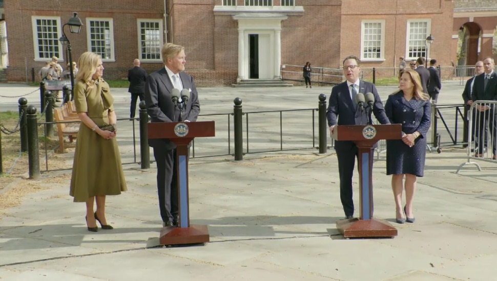King Willem-Alexander and Josh Shapiro standing at separate podiums, along with their wives, Queen Máxima and Lori Shapiro.