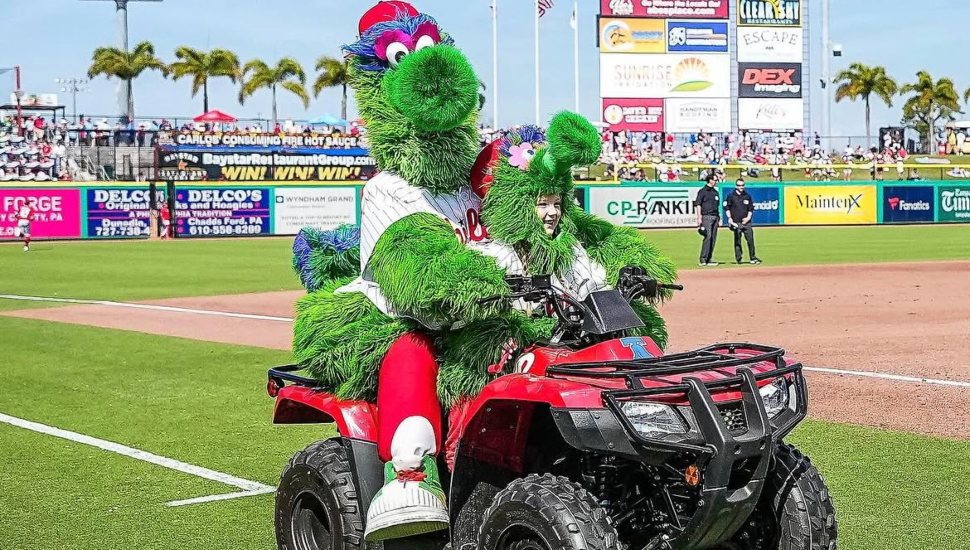 Phillie Phanatic on a bike with a child.