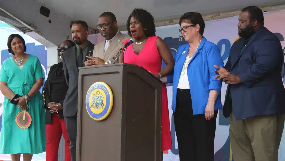 Cherelle Parker speaking at a podium, surrounded by Jazelle Jones, Vanessa Garrett Harley, Sharif Street, Kenyatta Johnson, Kathryn Ott Lovell, and Jordan Harris.