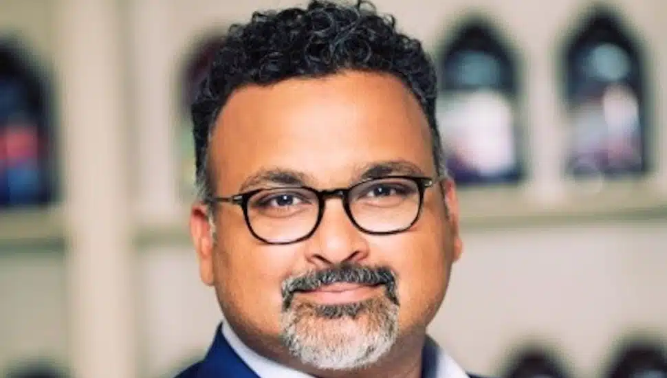 Bobby Chacko, CEO of Bonduelle Americas, wearing glasses and a blue suit jacket, poses for a professional headshot.