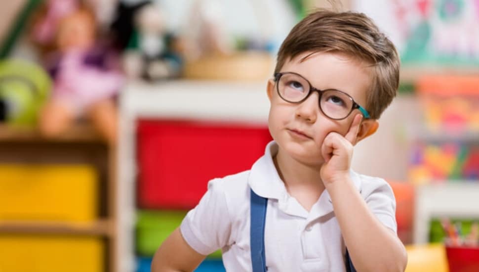 Young boy with glasses in a classroom.