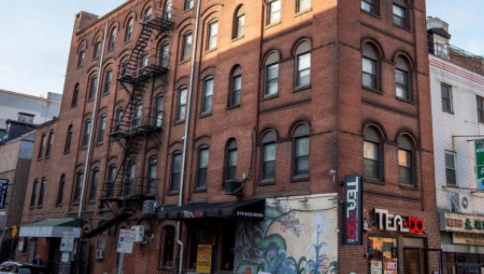 Five-story red brick Victorian factory building with arched windows and a fire escape, located at the corner of 10th and Cherry streets in Philadelphia's Chinatown neighborhood.