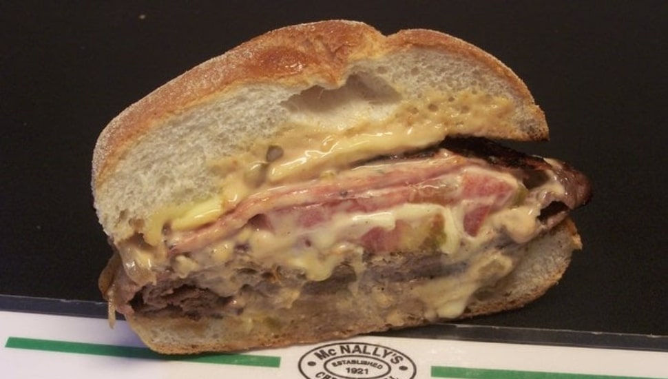 A close-up of the Schmitter sandwich at McNally's Tavern in Chestnut Hill, Philadelphia, showing layers of steak, salami, melted cheese, and sauce on a toasted Kaiser roll.