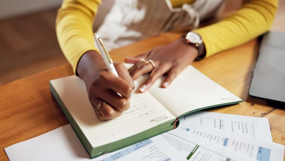 Woman writing in notebook for to-do list.