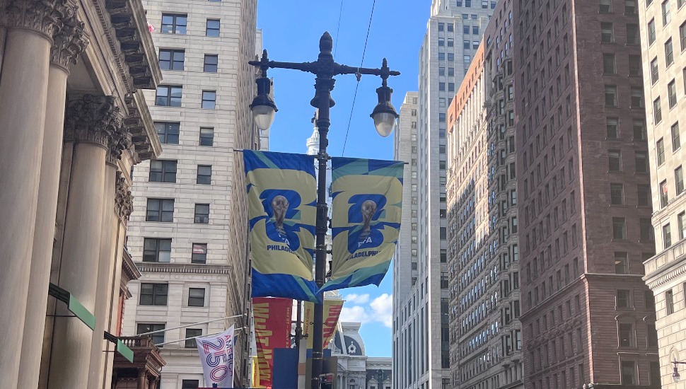 FIFA World Cup banners reading "Philadelphia" hang from a streetlight on a Center City street lined with historic buildings.