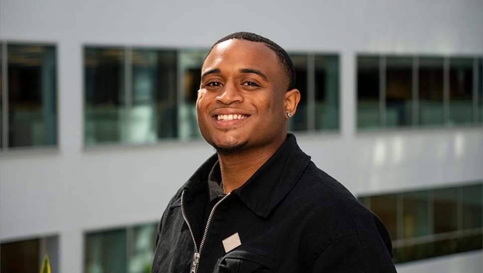 Khamani Wade, Rutgers–Camden student and FIFA Rising Stars Academy participant, smiles in front of a modern building.